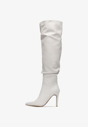 Knee-high white leather boots with a slouch design, pointed toe, and a stiletto heel. Smooth texture and minimalistic style.
