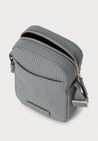 Μικρή γκρι τσάντα χιαστί με πλεκτή υφή, μπροστινή τσέπη, ασημένιο φερμουάρ μισάνοιχτο και ρυθμιζόμενο λουρί με μεταλλική αγκράφα.