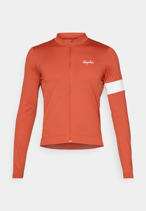 Cyklistický dres s dlouhým rukávem v barvě rezaví, vyrobený z lehkého materiálu. Obsahuje přední zip a bílý pruh na levém rukávu; logo na hrudi.