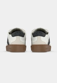 Ténis de couro branco com detalhes em tecido cinza, sola de borracha cor de bege clara e detalhes texturizados no calcanhar traseiro.