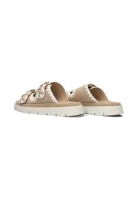 Beige suède sleefsandalen met witte geborduurde bloemaccenten, dubbele goudkleurige gespen en een dikke witte rubberen zool met geribbeld patroon.