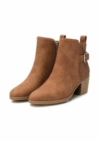 Stivaletti marroni alla caviglia in suede con una texture liscia, punta affusolata e tacco basso a blocco. Presentano cuciture decorative e dettagli perforati sui lati.