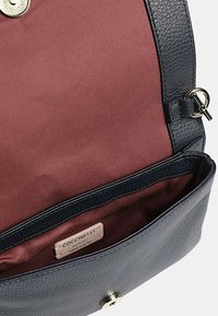 Borsa in pelle grigia con superficie testurizzata, fodera in tessuto bordeaux, accessori metallici e un'etichetta di marca visibile all'interno del compartimento principale.