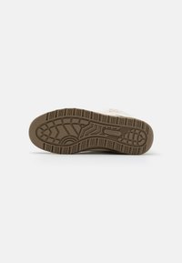Suela de zapato color crema con una suela de goma marrón texturizada. Presenta patrones de relieve intrincados para un mejor agarre y durabilidad, incluyendo acentos elevados.