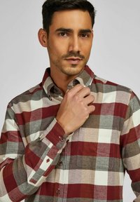 Geruit flanellen overhemd met rode, grijze en crèmekleurige vierkanten. Zachte textuur, knoopsluiting en een borstzakje.