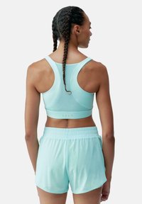 Lichtblauw sportbh met racerback ontwerp en ademend mesh. Gepaard met lichtblauwe shorts met elastische tailleband, beide gemaakt van zachte stof.