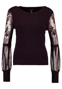 Bordeaux trui van ribbelstof, voorzien van doorschijnende kanten lange mouwen versierd met bloempatronen, nauwsluitende manchetten en een ronde halslijn.