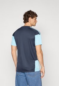 Navy and light blue short-sleeve athletic jersey, featuring a crew neck and contrasting side panels, made of smooth, breathable fabric.