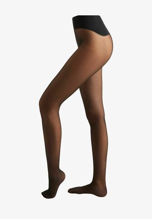 Gamba destra leggermente sollevata sulle punte, con collant neri trasparenti e cinturino opaco nero, su sfondo bianco.