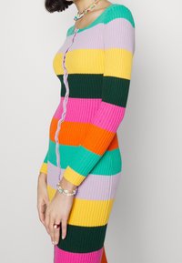 Vestido de punto acanalado con rayas verticales en rosa, amarillo, verde, naranja y turquesa. Incluye un escote redondo y botones en la parte delantera.