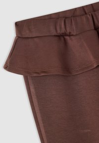 Pantaloni marroni leggeri con vita arricciata. Presentano una texture morbida e dettagli cuciti lungo il bordo della riga.