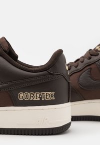 Zapatillas de cuero marrón y malla con marca Gore-Tex. Punta redonda, cuello acolchado, mediasuela blanca y suela de goma texturizada.