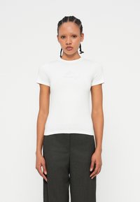 T-shirt bianco fitted in cotone morbido con maniche corte e scollatura rotonda, caratterizzato da un sottile ricamo "Mixed Feelings" sul petto.