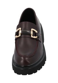 Mocassini in pelle bordeaux con una fibbia oro e nera; presentano una suola chunky nera e dettagli in cucitura rossa lungo i bordi.
