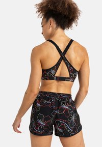 Black floral sports bra with a cross-back design and adjustable straps, paired with matching black shorts featuring colorful floral patterns.