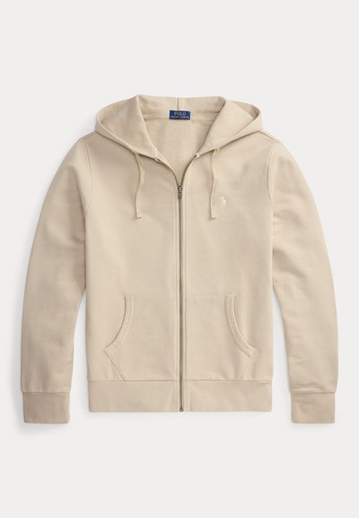 Beige zip-up hoodie with drawstring hood, front pockets, and subtle embroidered logo on left chest, laid flat on white background.