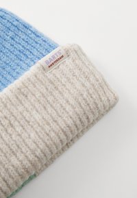 Knit beanie with a light blue top and cream ribbed cuff. Features a BARTS label sewn into the cuff. Soft texture, warm design.