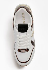 Białe sneakersy z błyszczącymi brązowymi akcentami w print zwierzęcy, okrągłym noskiem i białymi sznurówkami. Zawierają czarny element z tyłu i złoty detal z logo.