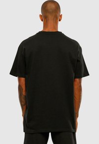 Black oversized cotton T-shirt with short sleeves, a round neckline, and a smooth texture; no visible logos or patterns.