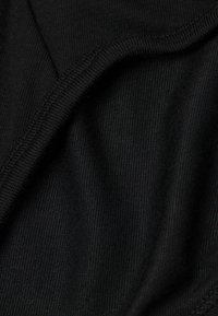 Schwarzer Stoff mit einer glatten, feinen Textur und leichtem Glanz. Die Nahaufnahme zeigt subtile Nähdetails und drapierte Falten, die Flexibilität anzeigen.