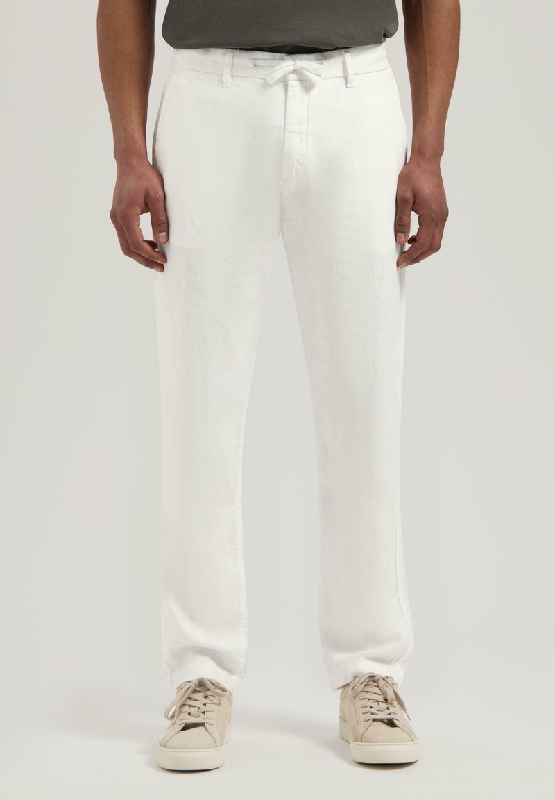 Hvite linbukser med rett ben, med snøring i livet og subtil tekstur. Kombinert med beige sneakers.