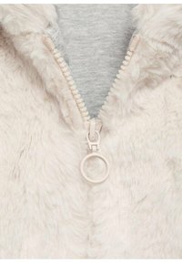 Faux-Fur-Reißverschlussjacke in sanftem Beige mit einem runden Reißverschlussanhänger, mit einer grauen Stoffauskleidung darunter. Glatte, strukturierte Oberfläche.