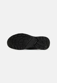 Sole di scarpa sportiva nera con gomma testurizzata per grip, caratterizzata da un motivo a rilievo e un design del tallone curvo. Materiale leggero e durevole.