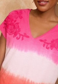 Vaaleanpunainen ja valkoinen ombre V-kaula-aukkoshirt, jossa on kukkakirjontaa hartioilla. Pehmeä kangas, rento malli ja lyhyet hihat.