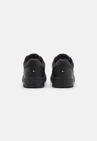 Czarne trampki z gładką skórzaną i materiałową cholewką, okrągłym obcasem, gumową podeszwą oraz małym, wielokolorowym logo po boku.