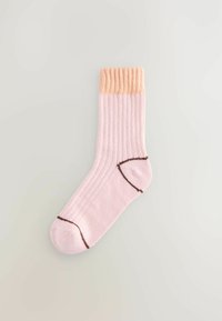 Light pink ribbed sock with a peach-colored cuff, featuring brown stitching along the toe and heel areas.