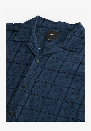 Navy blue button-up shirt with a textured, embroidered square pattern and a collar. Features four buttons and a brand label inside.