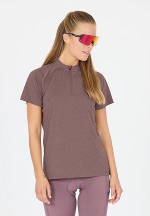 Korte mouw, lichtbruine fietsjersey met een ritssluitingkraag, gebreide stof, gecombineerd met roze getinte zonnebril en bijpassende legging.