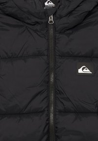 Fekete steppelt dzseki középső cipzárral és Quiksilver logóval a mellkason és címkén a galléron.