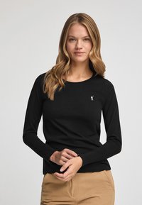 Svart långärmad t-shirt i bomull med rund halsringning, med en liten vit logotyp på bröstet och en figurnära silhuett.