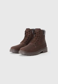 Botas de cuero marrón hasta el tobillo con diseño de cordones, punta redonda, collar acolchado y suela de goma texturizada con estrías para agarre.