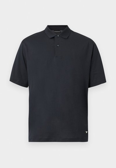 Μαύρο πόλο με κοντά μανίκια, με δύο κουμπιά και μικρό λογότυπο στο κάτω αριστερό στρίφωμα.