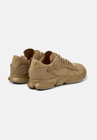 Sneakers in pelle beige con dettagli in suede, punta tonda, suola in gomma spessa e design minimalista. Lacci e linguetta sul retro.