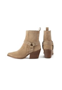 Tan suede ankle boots featuring a pointed toe, ribbed details, a decorative strap with hardware, and a stacked heel.