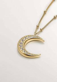 Collar con colgante en forma de media luna dorada adornada con cristales transparentes a lo largo de la curva, suspendida de una delicada cadena con acentos de cuentas.