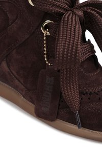 Καφέ σουέντ αθλητικό παπούτσι με υφαντή υφή, που διαθέτει μεγάλο πλεγμένο κορδόνι και χρυσό μεταλλικό τρύπα, καθώς και ετικέτα με ανάγλυφη επωνυμία.
