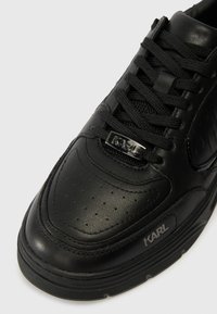 Schwarze Ledersneaker mit abgerundetem Zeh, schwarzen Schnürsenkeln, metallischem "KARL"-Tag an der Vorderseite und "KARL"-Druck an der Seite der Sohle.