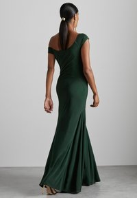 Zelená off-shoulder večerná šaty s priliehavým korzetom a rozšírenou sukňou. Vyrobená z hladkej tkaniny, s jemným leskom a dĺžkou sukne po kolená.