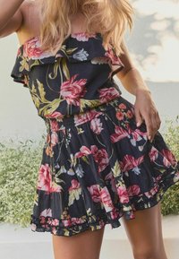 Šaty s květinovým vzorem v tmavé látce, s volánkovým výstřihem, smockovaným pasem a vrstvenou sukní s vlnkovým lemem.