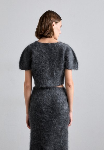 Completo in maglia grigia fuzzy a due pezzi, composto da un top corto con maniche a sbuffo e una gonna midi aderente, che mette in risalto una texture morbida.