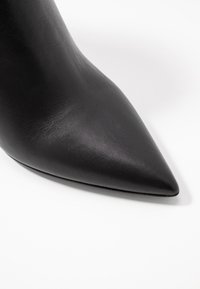 Sorte læder højhælede sko med spids tå og en glat tekstur samt en forlænget silhuet, der fremhæver det slanke design og finish.