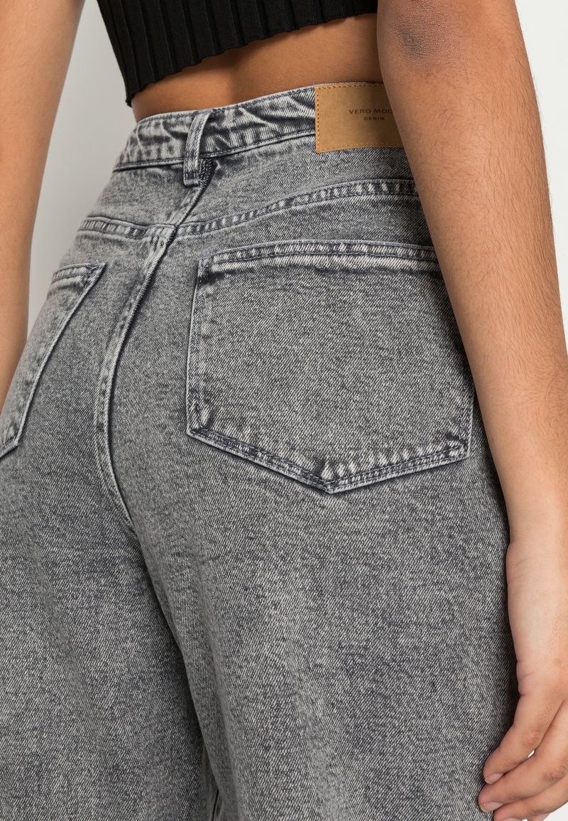 Graue Jeans aus Denim mit strukturiertem Finish, hoher Taille und Fünf-Taschen-Design. Mit einem sandfarbenen Etikett am hinteren Taillenbund.