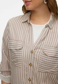 Bruin gestreept shirt met korte mouwen, voorzien van twee borstzakken, een kraag en gouden knopen, gemaakt van een lichtgewicht, gestructureerde stof.