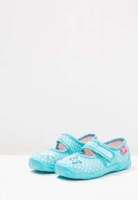 Turquoise stoffen schoenen met witte stippen, Mary Jane-stijl, met een klittenbandsluiting, roze binnenvoering en decoratieve stiksels.