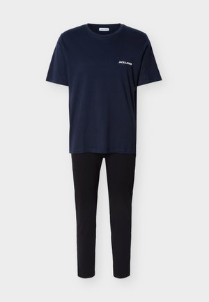 Tamsiai mėlyna trumpomis rankovėmis marškinėliai su mažu baltu "JACK & JONES" logotipu krūtinės srityje, derinami su paprastomis juodomis siaurutėmis kelnėmis.