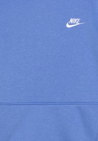 Ljusblå sweatshirt gjord av mjukt tyg, med en liten vit Nike-logotyp på övre vänstra sidan och en enkel, slät textur.